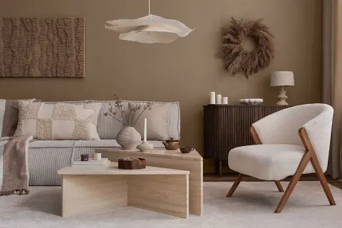 Przytulny salon w stylu naturalnym. Miękka sofa, puszysty fotel i kamienne stoliki tworzą oazę spokoju.