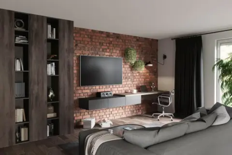 Nowocześnie urządzony salon z ceglaną ścianą, wiszącym TV, biurkiem i wygodną kanapą. Inspiracja, jak urządzić salon nowocześnie.
